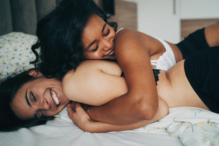 Two young women lying in bed together.