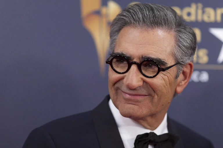 A man in round glasses and a black bowtie smiling.