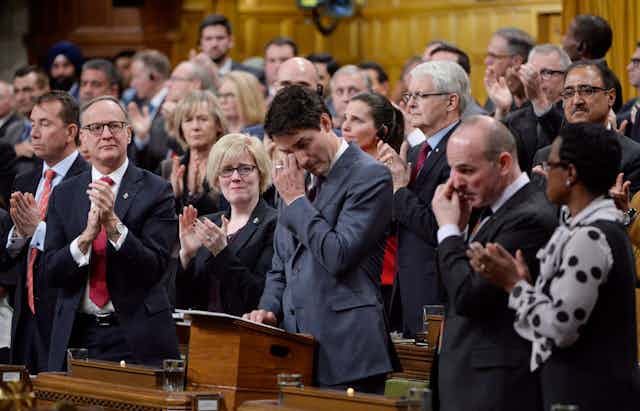 Justin Trudeau wipes a tear from his eye as other parliamentarians clap around him