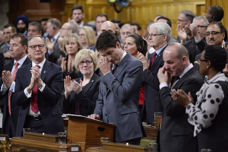 Justin Trudeau wipes a tear from his eye as other parliamentarians clap around him