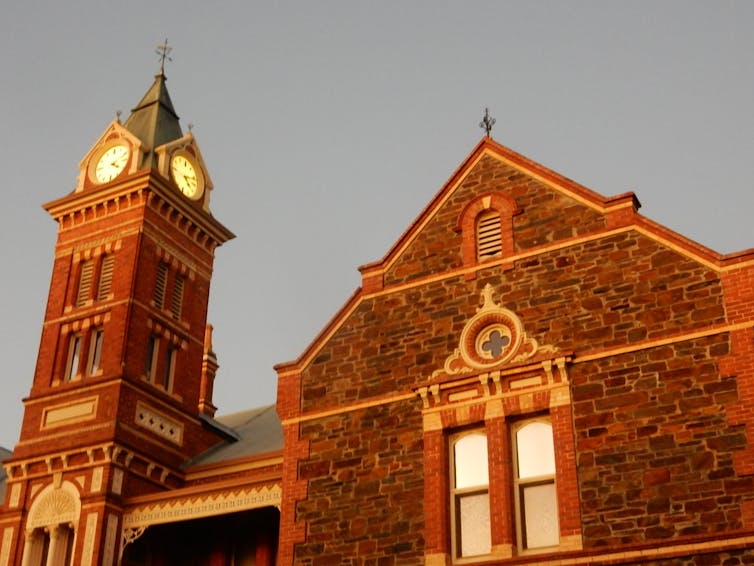 View of clocktower of bluestone building at sunset.