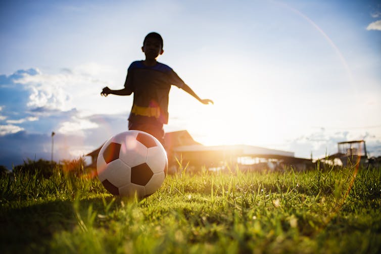 Boy kicking soccer ball.