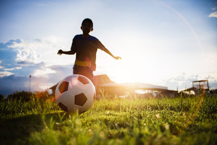 Junge, der Fußball tritt.