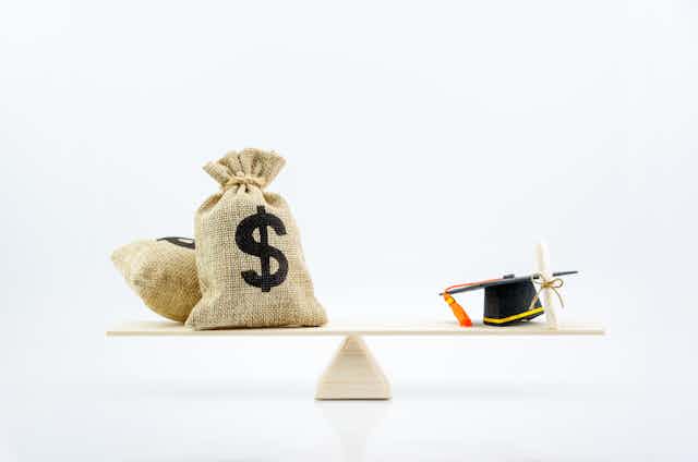 bags of money balanced against academic degree 