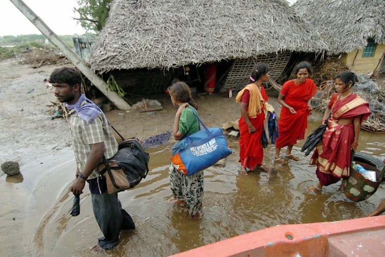 People leave the devastated Karmavadi village with their belongings in the Nagapattinam district, some 350 km south of Madras, 27 December 2004, after tidal waves hit the region