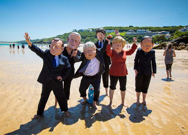 Protesters dress as G7 leaders on a Cornish beach.