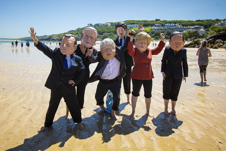 Protesters dress as G7 leaders on a Cornish beach.
