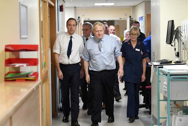 Matt Hancock and Boris Johnson walking through an NHS corridor