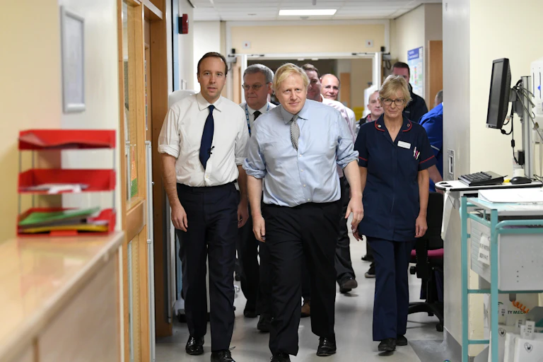 Matt Hancock and Boris Johnson walking through an NHS corridor