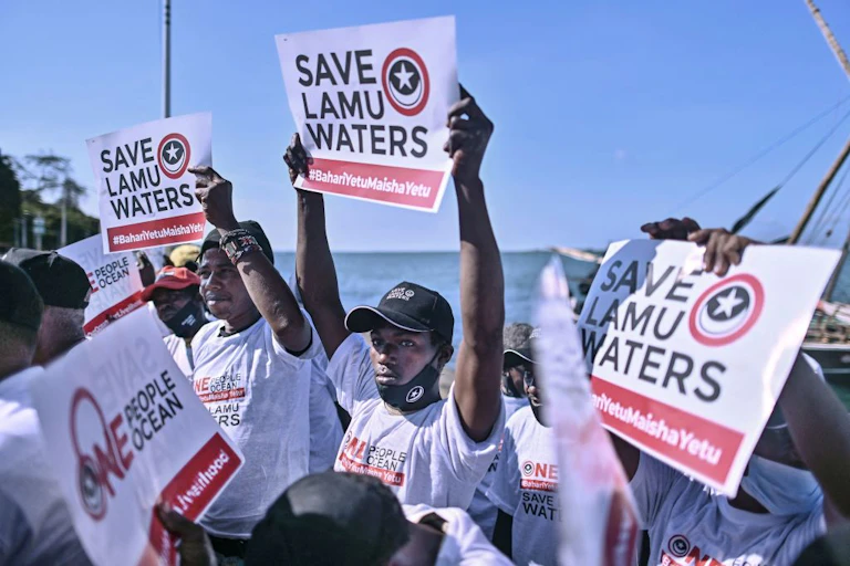 Kenyan fishermen carry placards off the Lamu coast
