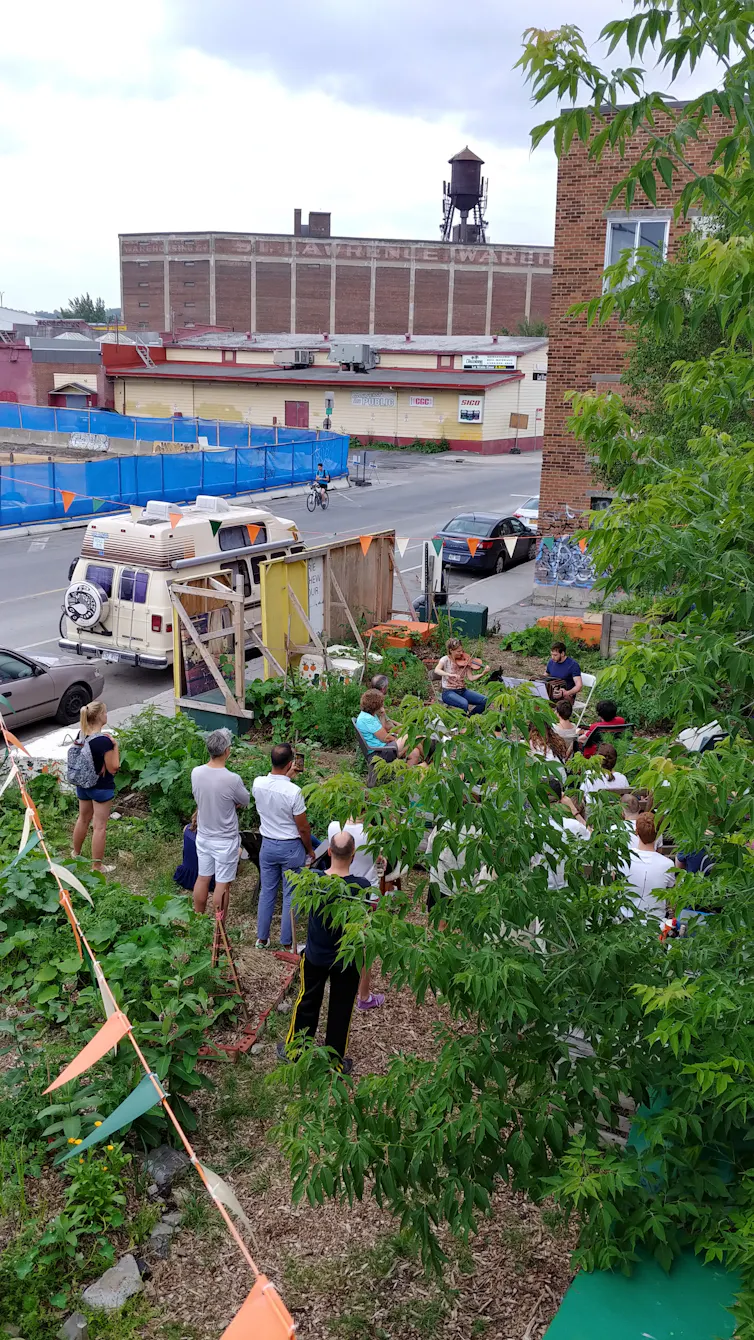 Des gens sont regroupés autour d’un jardin, dans une zone industrielle de la ville