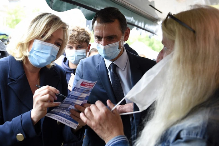 Marine Le Pen signe un tract le 8 juin 2021, lors d'une visite dans un marché de Lunéville aux côtés de la tête de liste RN dans le Grand Est, Laurent Jacobelli.