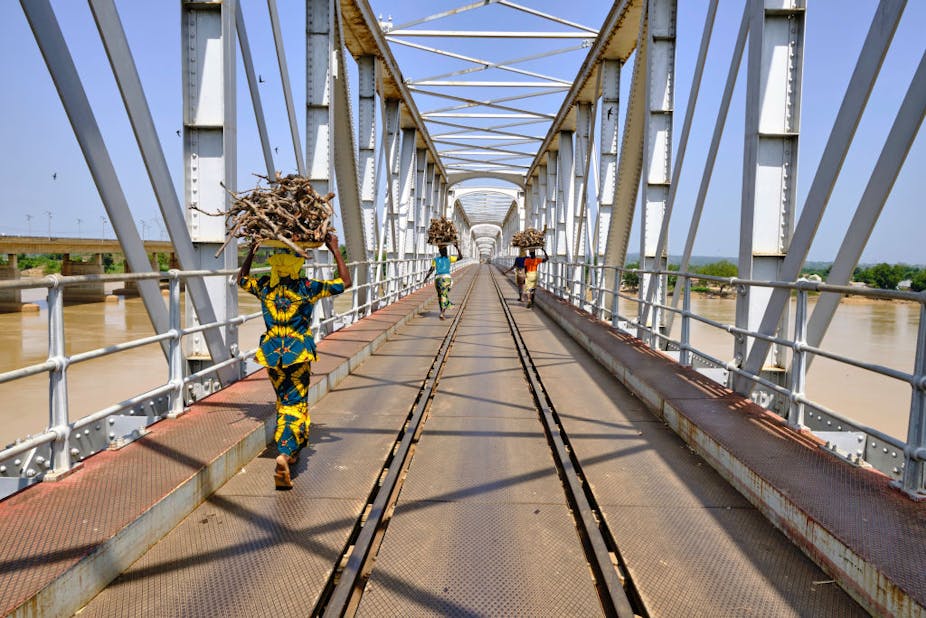 Women with a load on their head crossing river Niger using the railway bridge at Jebba