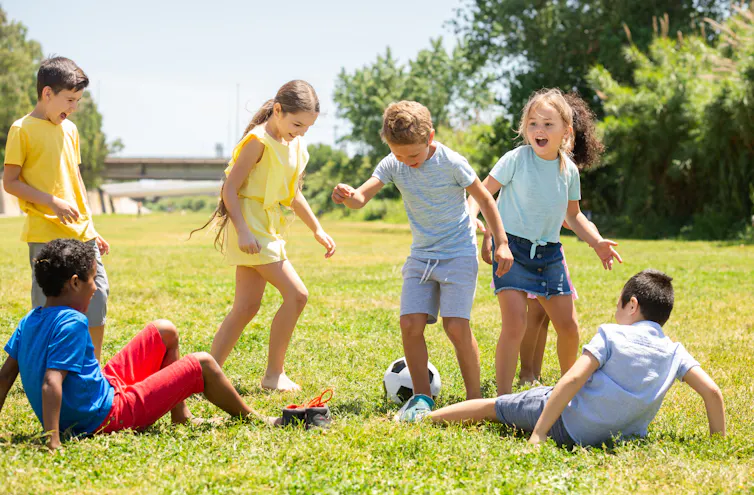 Group of children playing football outdoors in the summer.