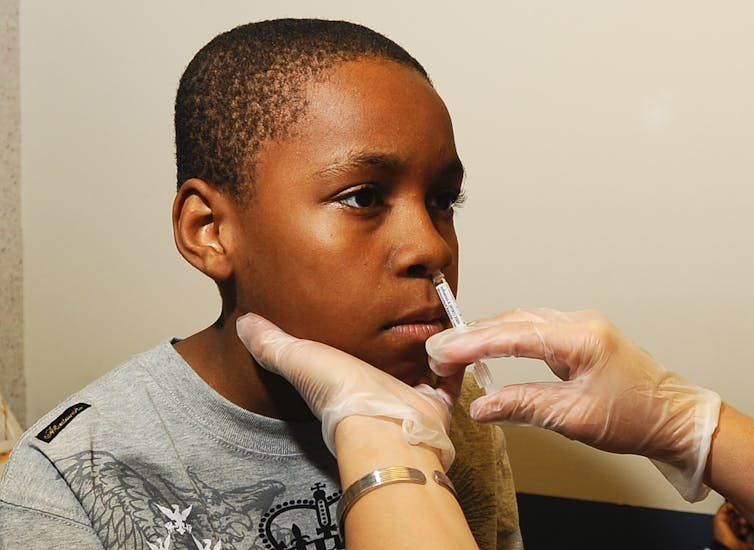 Un niño recibiendo una vacuna contra la gripe H1N1 mediante un spray nasal