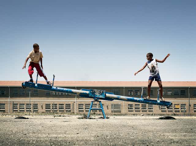 Two boy balancing on seesaw.