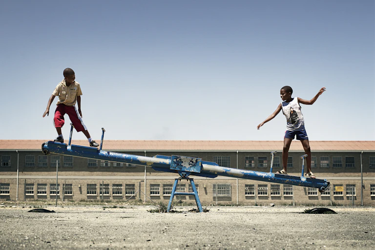 Two boy balancing on seesaw.