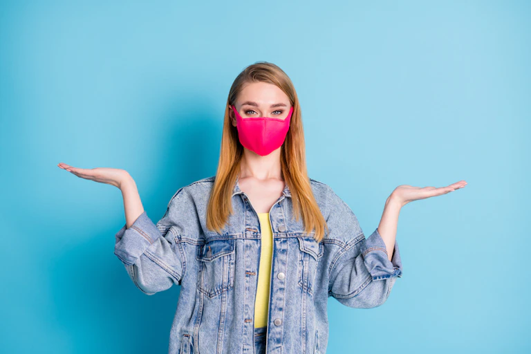 Young woman wearing mask with hands in air, undecided