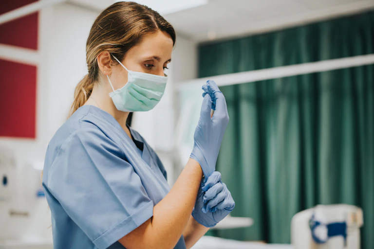 Nurse in mask putting on gloves.