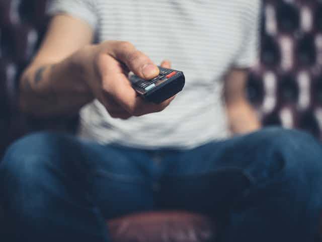 A man holds a TV remote.