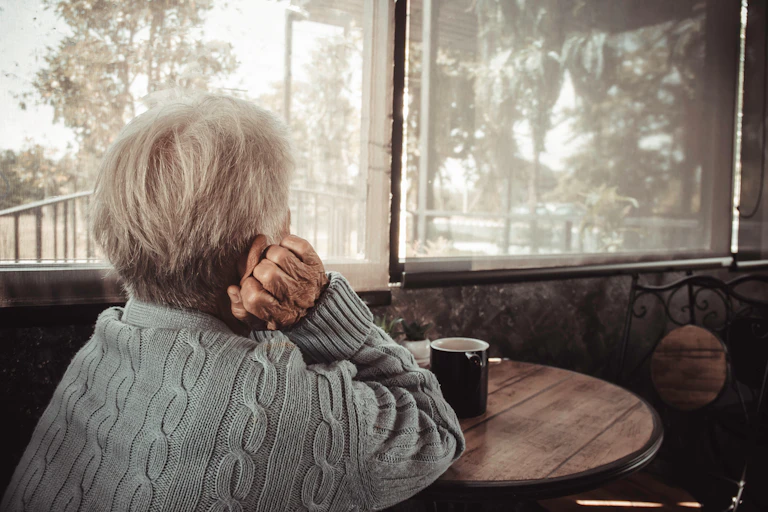 An elderly lady staring out the window