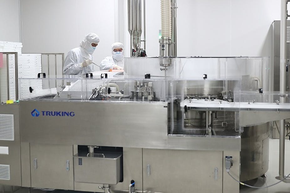 Two people in full protective gear work in a sterile laboratory type of room