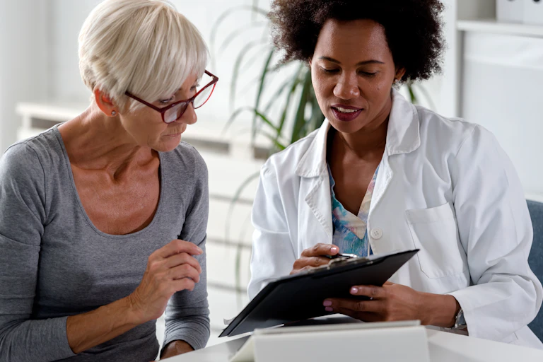 Female doctor using a clipboard to explain something to an older female patient.