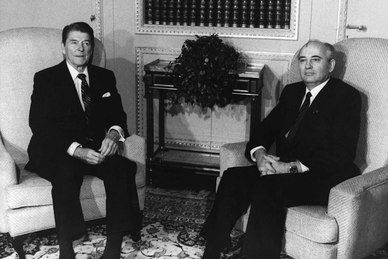 A black and white photo of Ronald Reagan and Mikhail Gorbachev seated in armchairs.