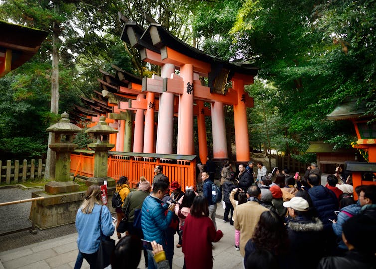 Tourists take the Senbon Torii path in the Fushimi Inari Taisha shrine in Kyoto, Japan