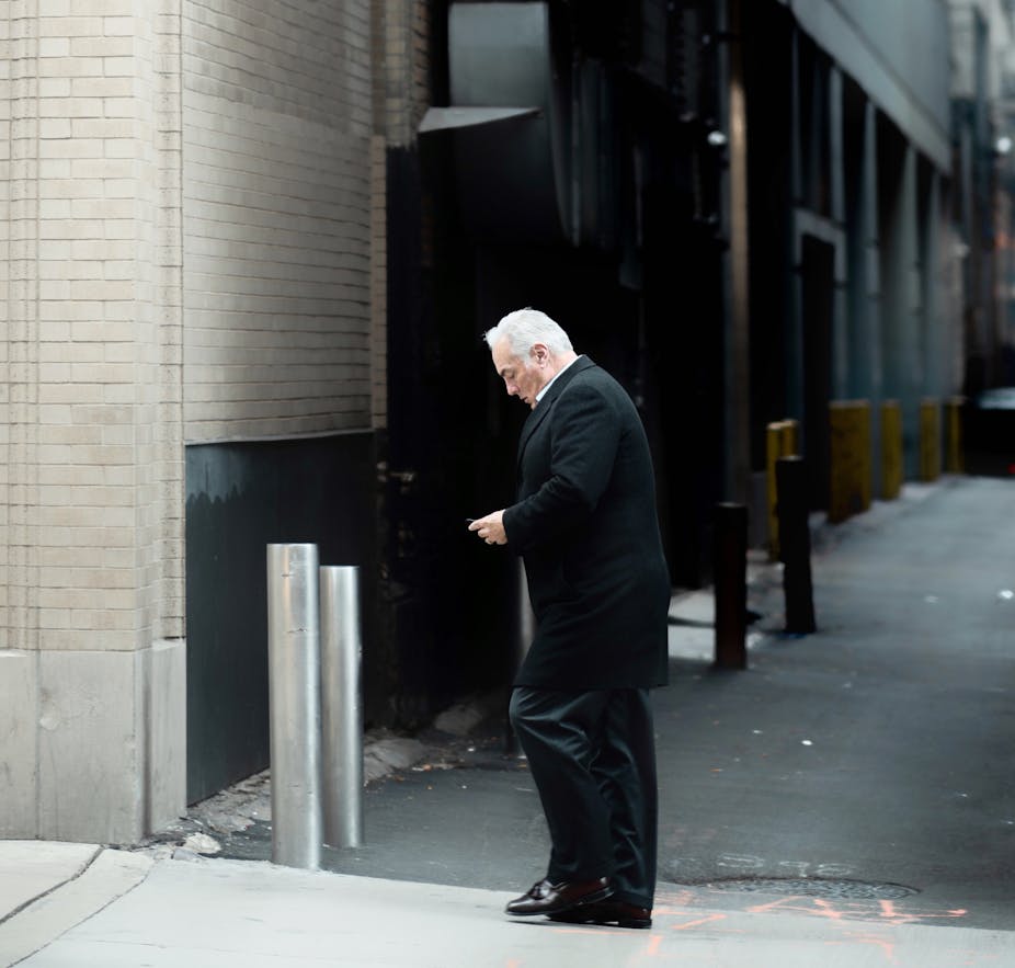 Older worker in an alley looking at his phone