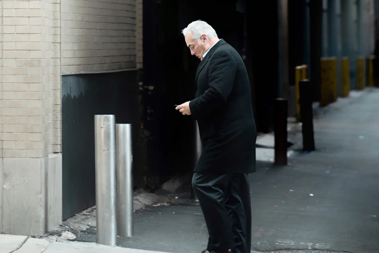 Older worker in an alley looking at his phone