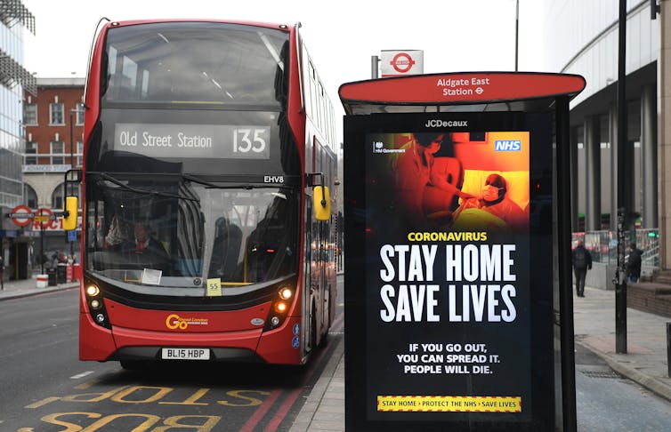 An advert on display at a bus stop in London reading 'stay home, save lives'