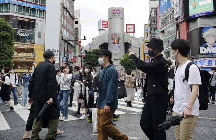 People wearing protective masks walk cross a crossway in Tokyo, Japan.