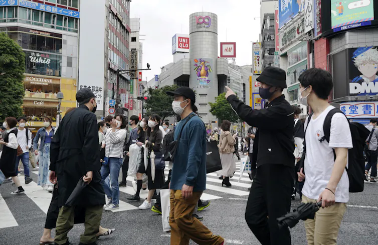 People wearing protective masks walk cross a crossway in Tokyo, Japan.