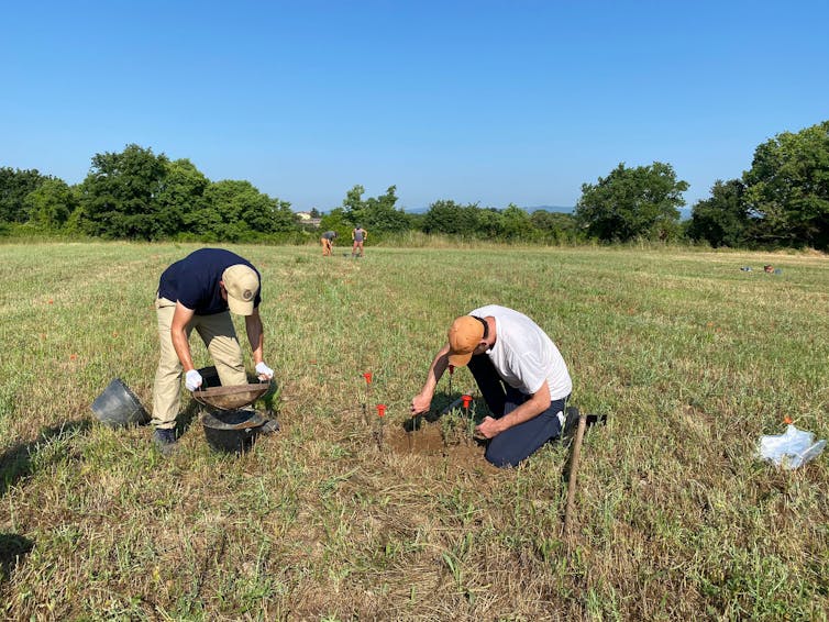 people sifting dirt in field