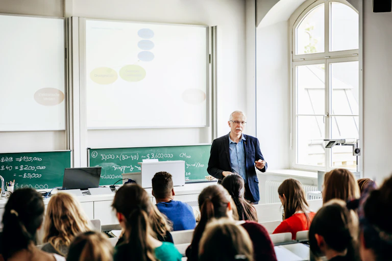 A white male professor teaches a class of students.