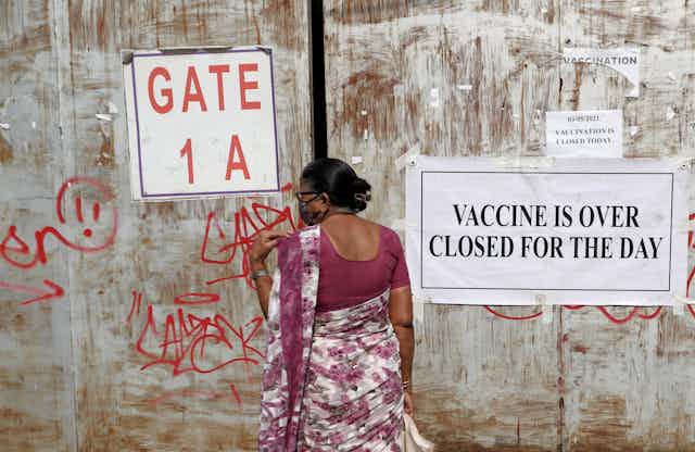 Woman standing next to a sign that says the vaccination centre is closed for the day.