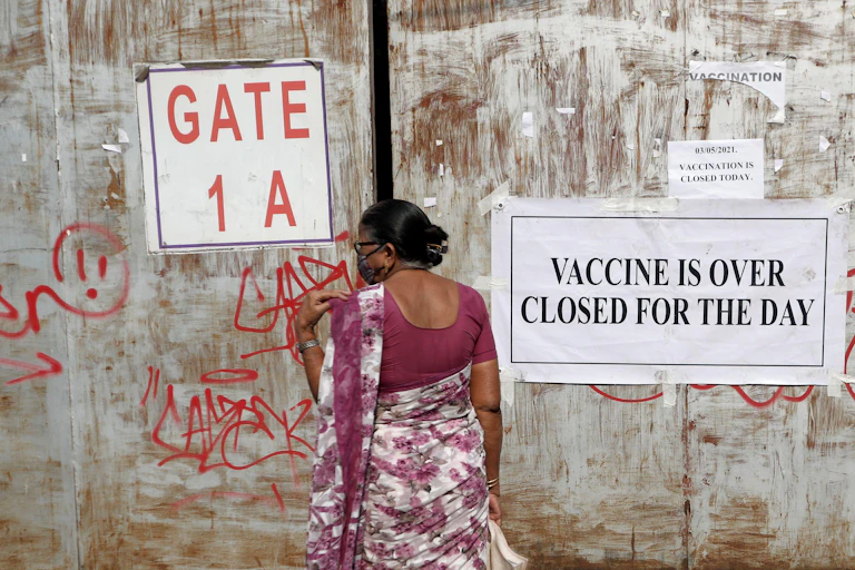Woman standing next to a sign that says the vaccination centre is closed for the day.