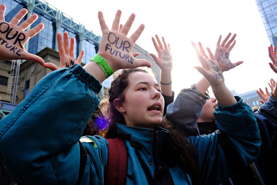 Students stand with their hands up, on their palms in sharpie reads 'OUR FUTURE'