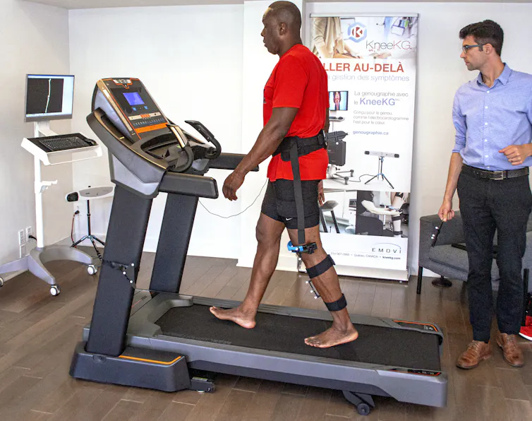 Bruny Surin marche sur un tapis roulant avec un harnais attaché à la jambe