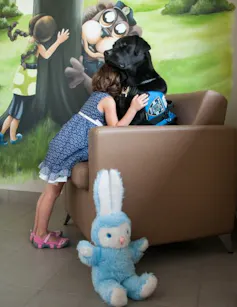 A child cuddles a black dog.