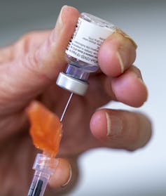 Hand filling a syringe from a vaccine vial