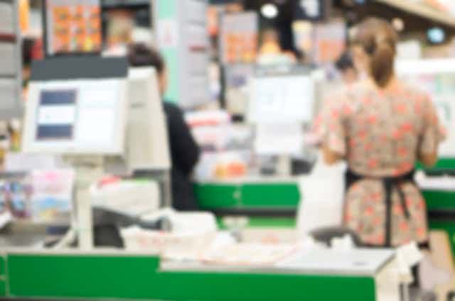 blurred supermarket checkout operator
