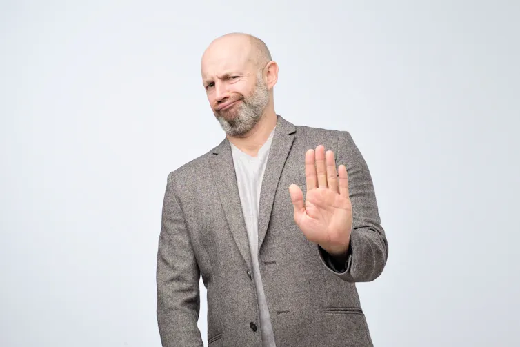 Man smirks as he holds out a hand to deny responsibility