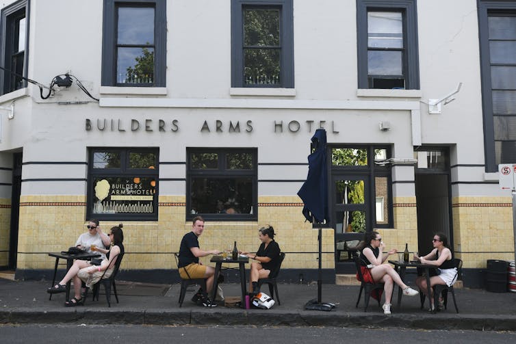 Patrons sit outside a pub.