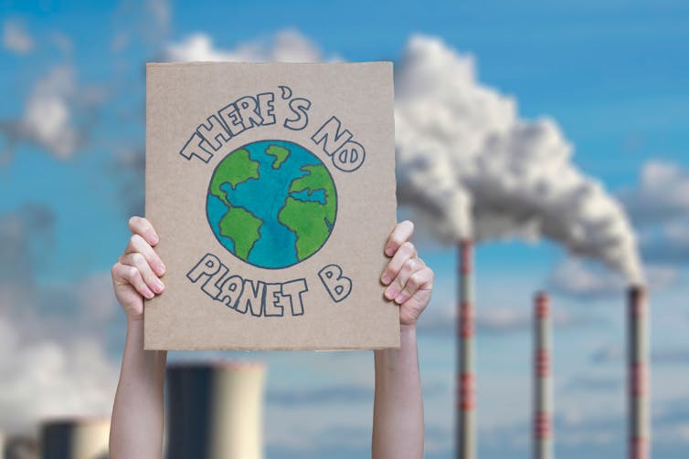'There's no Planet B' sign with smoke stacks