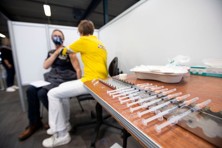 A man wearing facemask getting a COVID vaccine.