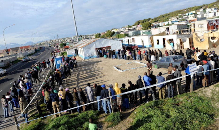Men and women stand in a long, winding voting queue in an informal settlement in Cape Town, South Africa in a long, winding voting