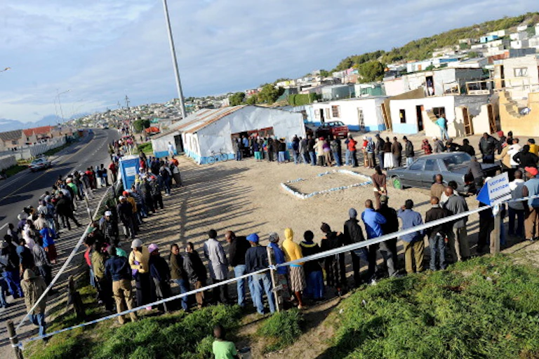 Men and women stand in a long, winding voting queue in an informal settlement in Cape Town, South Africa in a long, winding voting