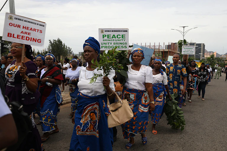 women marching peacefully on the streets with leaves and placards.